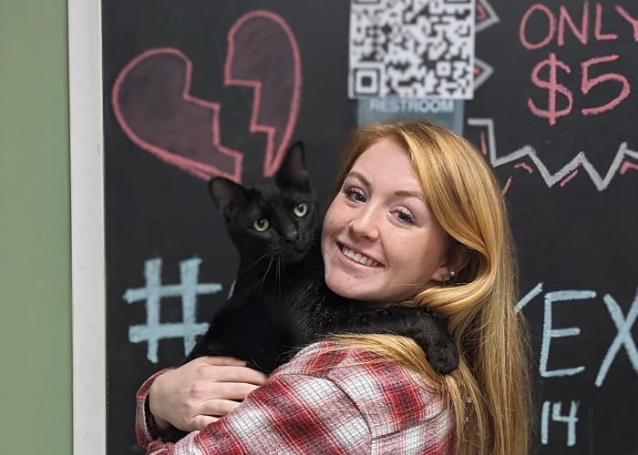 Photo of a woman holding a black cat she just adopted.