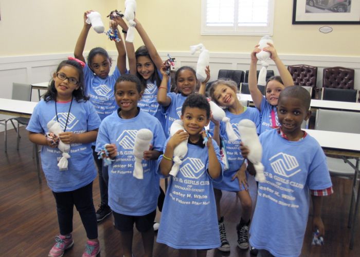 a group of smiling children hold up sock toys