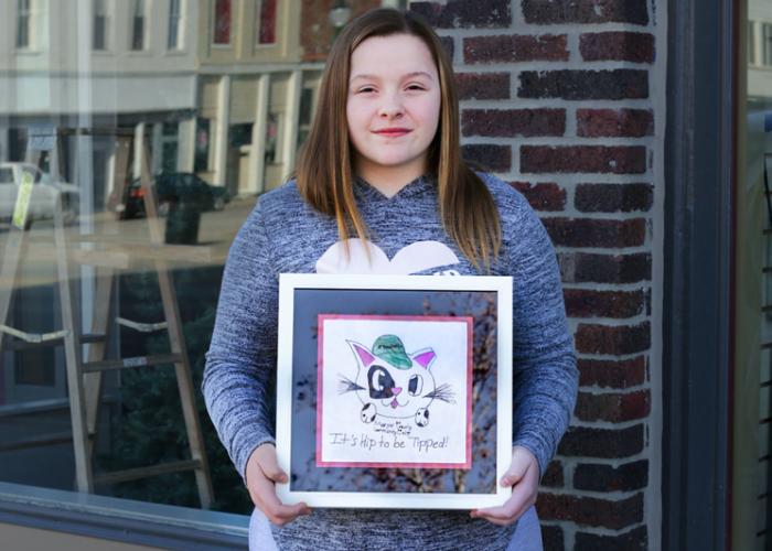 A girl poses with her contest winning drawing