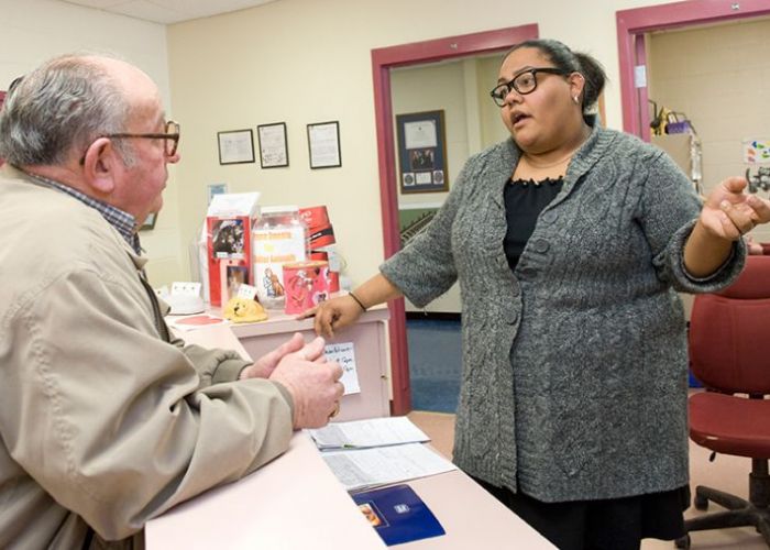 a woman standing behind a counter talking to an older man